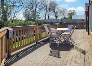 A wooden deck with a table and chairs, surrounded by a wooden fence.