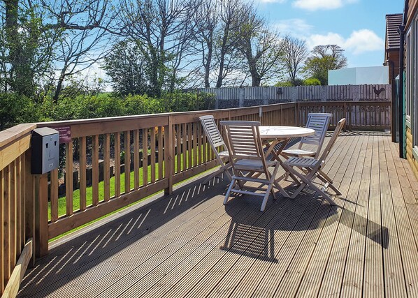 A wooden deck with a table and chairs, surrounded by a wooden fence.
