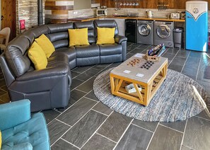 A modern living room with a sectional sofa, a coffee table, and a kitchen area with appliances.
