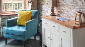 Een kamer met een blauwe fauteuil, een witte kast en een raam met uitzicht op groen.