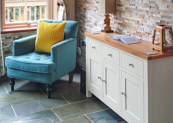 A room with a blue armchair, a white cabinet, and a window with a view of greenery. - 3 bedroom accommodation in Haswell, Nr Durham (Haswell, Nr Durham)