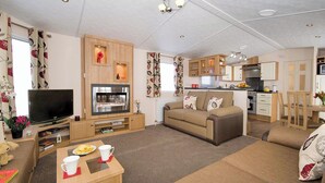 Un espace de vie compact comprenant un téléviseur, un canapé, une table à manger, un coin cuisine et une petite kitchenette.