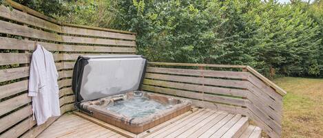 A wooden deck with a hot tub, a towel, and a wooden fence.