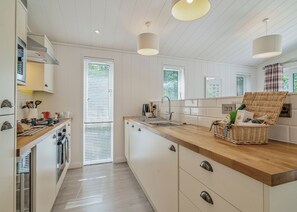 A modern kitchen with white cabinetry, a wooden countertop, and a wicker basket on the island.