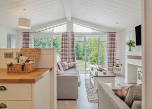 Et moderne køkken med en fletkurv, en grå sofa og et spisebord med en vase blomster.