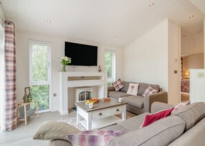 A modern living room with a flat-screen TV, a fireplace, a sofa, and a dining table.
