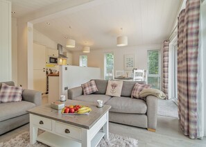 A modern living room with a sofa, coffee table, and a kitchen in the background. - Rabbits Warren Lodge (Cannington)