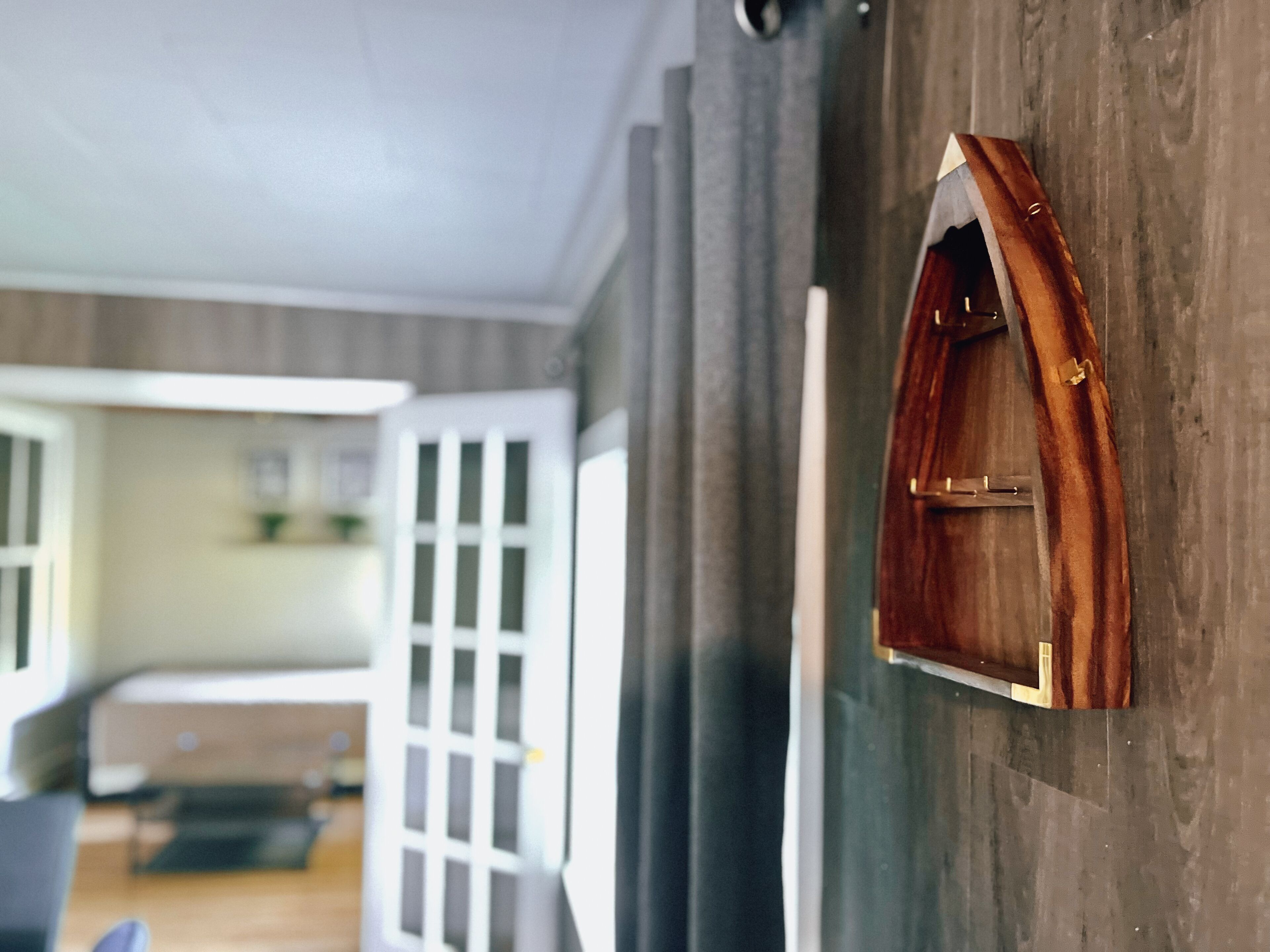 Une pièce avec un mur en bois, une petite porte en bois et une vue sur une autre pièce.
