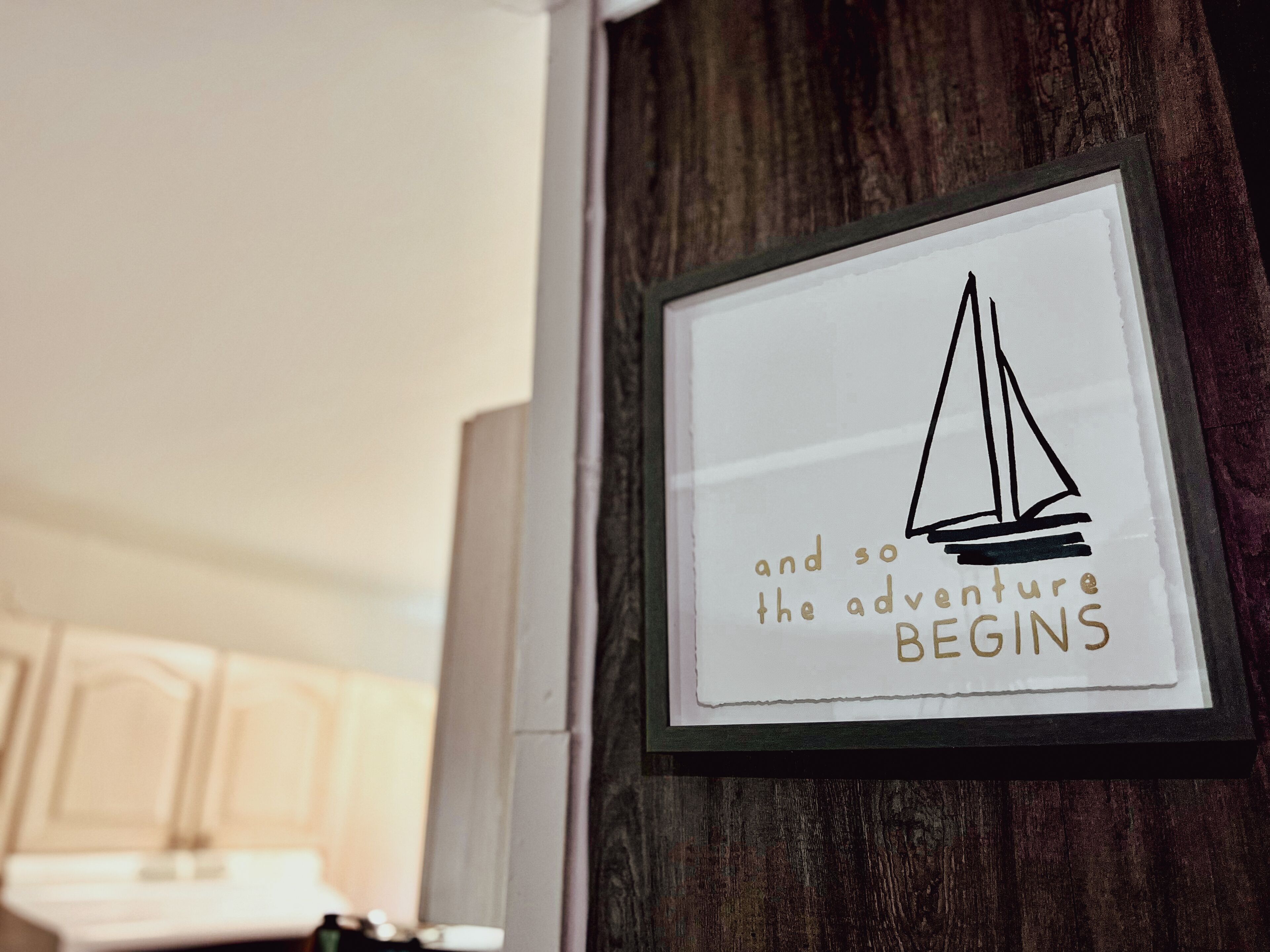 A framed inspirational quote on a wall with a sailboat illustration.
