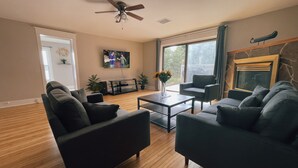 A modern living room with dark sofas, a coffee table, and a TV mounted on the wall. - Deer Hill Cottage on 5 Lake Chain (Haliburton)