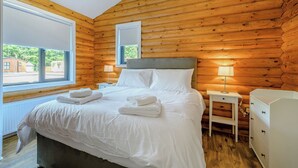 A wooden-paneled room with a bed, bedside tables, and a window. - 1 bedroom accommodation in Annbank, Ayr (Annbank, Ayr)