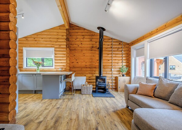 A log cabin interior with a kitchen, dining area, and a sofa.