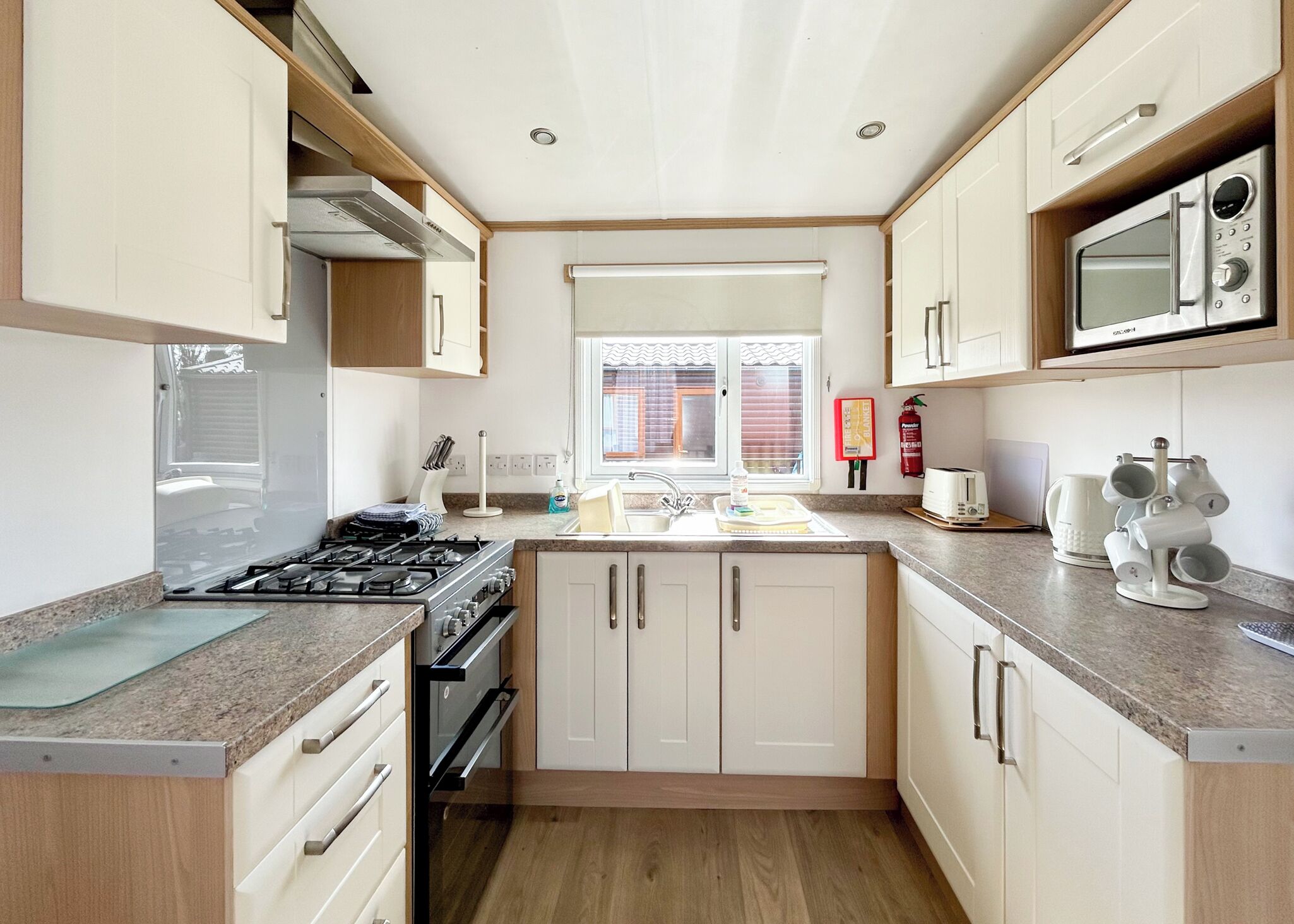 A compact kitchen with a gas stove, microwave, sink, and cabinets.