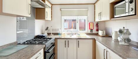 A compact kitchen with a gas stove, microwave, sink, and cabinets.