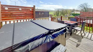 Eine überdachte Terrasse im Freien mit Trampolin, einem Tisch mit Stühlen und einem Holzzaun.
