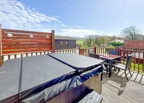 A covered outdoor deck with a trampoline, a table with chairs, and a wooden fence.