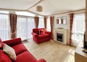 A living room with a red sofa, a fireplace, and large windows with curtains.