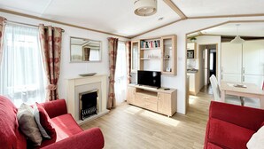 Ein Wohnzimmer mit Kamin, roten Sofas, einem Fernseher und einem Bücherregal.