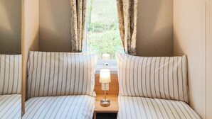 Una habitación con dos camas, una mesita de noche, una lámpara y cortinas.