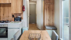 Cocina compacta con estufa a gas, tostadora y un cubo de basura.