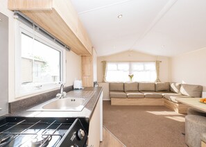 Cocina compacta con lavamanos, estufa y comedor con sofá y mesa.