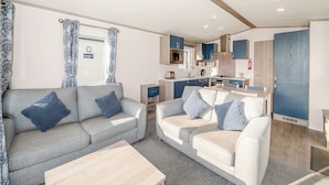 A compact living space with two sofas, a small kitchen, and a dining area.
