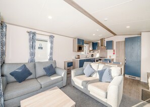 Un espacio habitable compacto con dos sofás, una pequeña cocina y una zona de comedor.