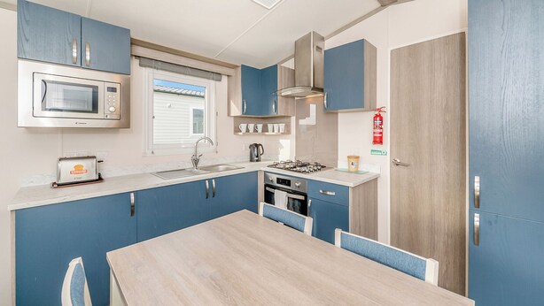 A compact kitchen with a microwave, toaster, sink, stove, and cabinets.