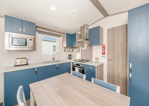 Una cocina compacta con microondas, tostadora, pileta, estufa y alacenas.