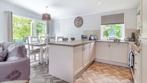 Eine moderne Küche mit einer zentralen Kochinsel, weißen Schränken und einem Essbereich mit Tisch und Stühlen.