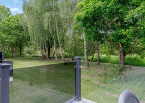 A grassy outdoor area with trees and a metal fence.