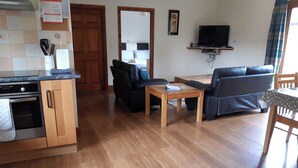 A living room with a sofa, a coffee table, and a television. - Lodge with fantastic contemporary styling. (Llanddewi, Nr. Llandrindod Wells)