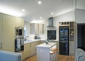 A modern kitchen with built-in appliances, a central island with stools, and a large refrigerator.