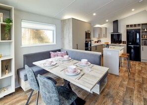 Une cuisine moderne avec un coin repas, un plancher en bois et des appareils électroménagers intégrés.