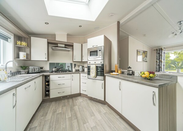 A modern kitchen with a skylight, built-in appliances, and a view of the outdoors.
