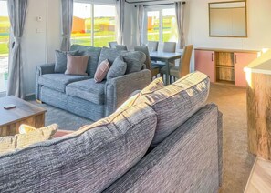 A modern living room with a sofa, a dining table, and a kitchen area.