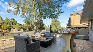 An outdoor patio with wicker furniture, a fire feature, and a table with drinks. - Beautiful Home Across the Street From ND (South Bend)