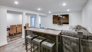 A modern living room with a bar area, a sofa, and a television mounted on the wall. - Beautiful Home Across the Street From ND (South Bend)