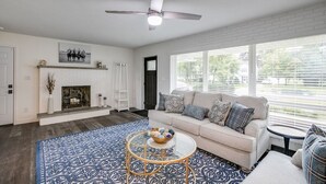 A living room with a fireplace, a sofa, a coffee table, and a ceiling fan. - Beautiful Home Across the Street From ND (South Bend)