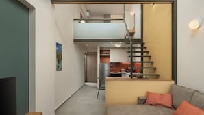 Una sala de estar moderna con un sofá, una mesa de centro y un televisor. Una escalera conduce a una zona de cocina.