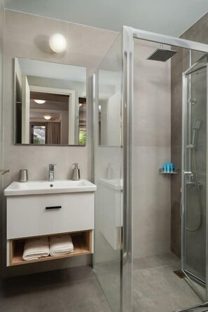 A modern bathroom with a white vanity, a large mirror, and a glass-enclosed shower.