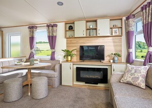 A cozy RV interior with a dining area, seating, a TV, and a fireplace.