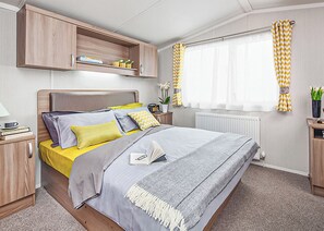 A modern bedroom with a bed, bedside tables, a wardrobe, and a window with curtains.