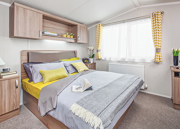 A modern bedroom with a bed, bedside tables, a wardrobe, and a window with curtains.