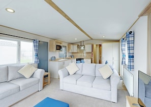 A compact RV interior with two sofas, a kitchenette, and a television.