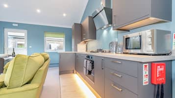 A modern kitchen with grey cabinets, a Bosch microwave, and a fire blanket on the wall.