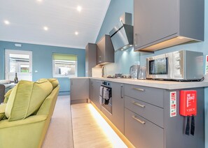 A modern kitchen with grey cabinets, a Bosch microwave, and a fire blanket on the wall.