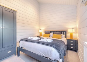 Ein Schlafzimmer mit einem Bett, Nachttischen, einem Kleiderschrank und einem Beistelltisch mit Lampen.