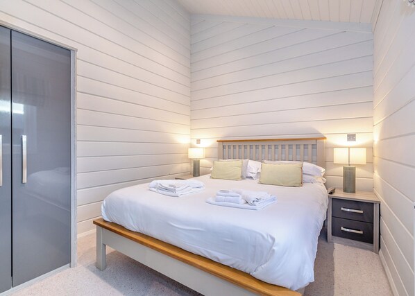 A bedroom with a bed, bedside tables, a bench, and a wardrobe.