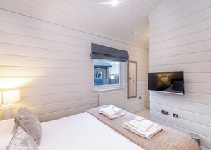 A hotel room with a bed, a TV, a window with a view, and a radiator.